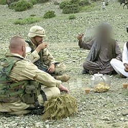 Afghan villagers share cookies and tea with Civil Affairs and 101st Airborne Division soldiers in 2002.