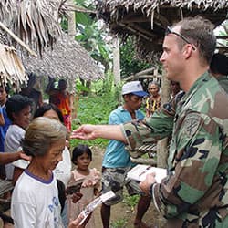 A PSYOP soldier distributes pamphlets to Filipino villagers in November 2003.