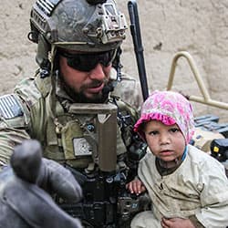 A Special Forces soldier makes a new friend at a medical clinic in Afghanistan, 2013.