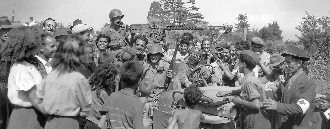 Radcliffe’s patrol is greeted by cheering Romans. Radcliffe is the soldier in the passenger’s seat of the jeep (the soldier in the center of the photograph with the rifle and the Italian hugging him).