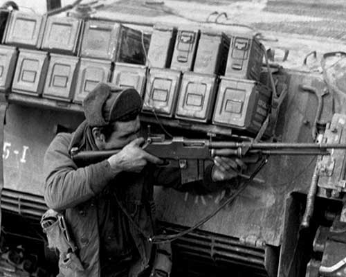 Taking cover behind their tank escort, one man of this ranger patrol of the 5th RCT, U.S. 24th Infantry Division, uses his BAR to return the heavy Chinese Communist small arms and mortar fire which has them pinned down on the bank of the Han River.