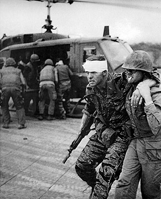 First Lieutenant (1LT) Paul R. Longgrear, the Mobile Strike Force (MSF) company commander at Lang Vei, is helped to the Marine Aid Station at Khe Sanh Combat Base, 7 February 1968.
