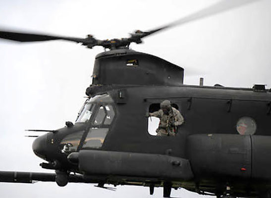 An MH-47G Chinook crew chief checks the final approach of his helicopter, skills attained during the 86-day Non-rated Crewmember (NRCM) course provided by Company B, SOATB.