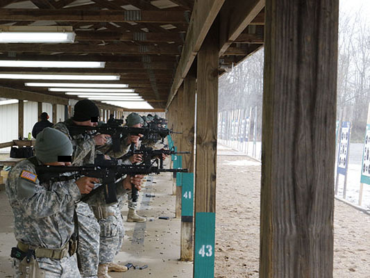 A SOATB-assigned contractor observes soldiers firing M4 carbines during the Weapons phase of the Combat Skills course.
