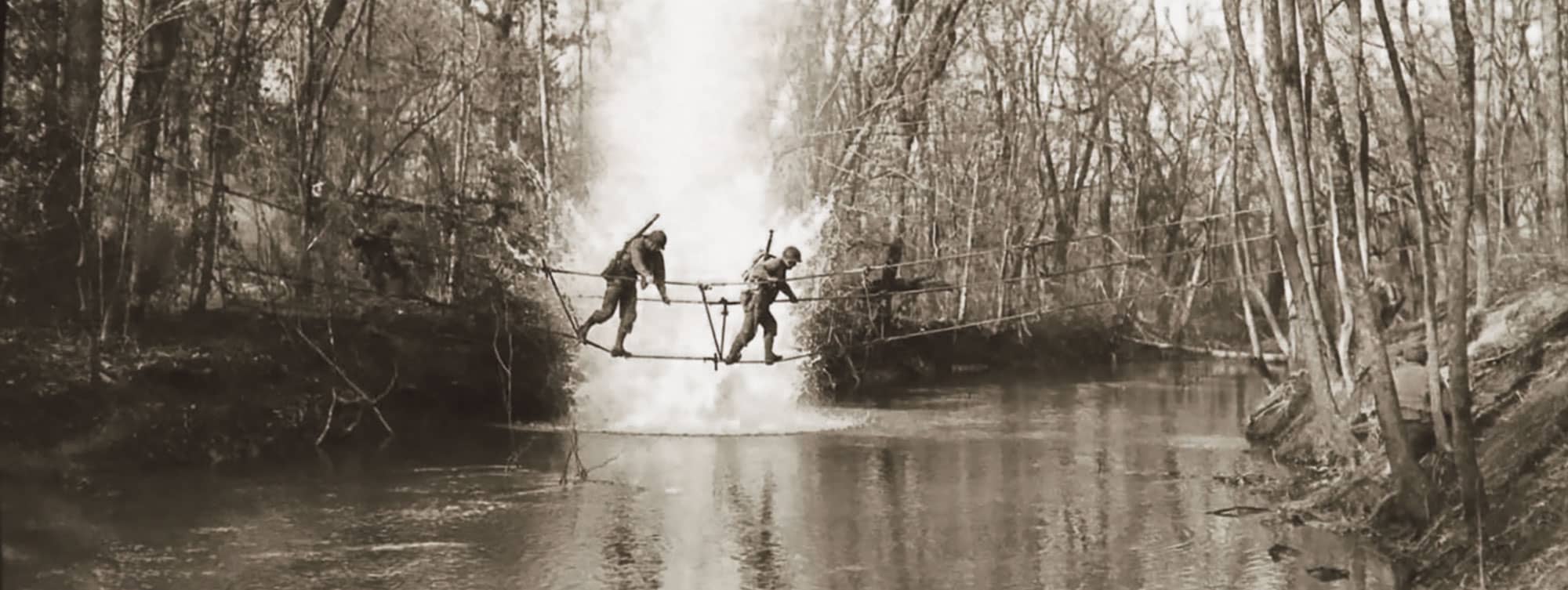 Second Army Rangers cross a stream on a toggle-rope bridge under simulated battle conditions. This demostration occured at Camp Forrest, Tennessee, on 23 January 1943.