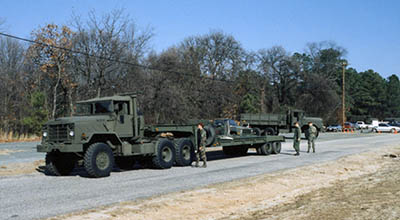 SPC Nathan W. Creamer and PFC Scott J. Meyer inspect one of the Transportation Detachment’s two M931 5-ton tractors, with 25-ton low bed trailer. 1LT Robert T. Davis supervises.
