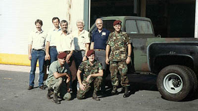 SPC Rancourt, SPC Driscoll, and LTC David L. Shaw, 528th SOSB Commander, pose in front of the completed dual-wheeled M-1028 prototype in September 1988. The civilians pictured are General Motors technicians and engineers, who helped with the project.