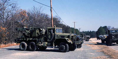 In the foreground is a second-hand M816 wrecker belonging to the Maintenance Detachment. A new-issue M923 5-ton cargo truck can be seen in the background.