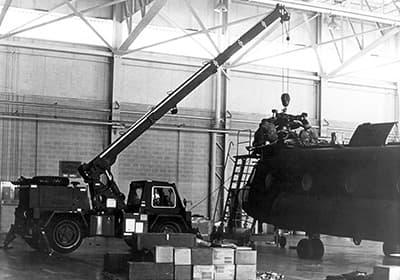 A Grove model RT4451 4-ton Self Propelled Crane for Aircraft Maintenance and Positioning (SCAMP) is being used to remove a component from one of the Chinooks. A single SCAMP serviced both airframes.