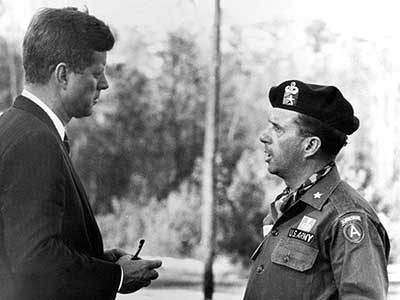 JFK speaks with Brigadier General William P. Yarborough, Commanding General, U.S. Army Special Warfare Center and School, during his visit to Fort Bragg, NC, in October 1961.