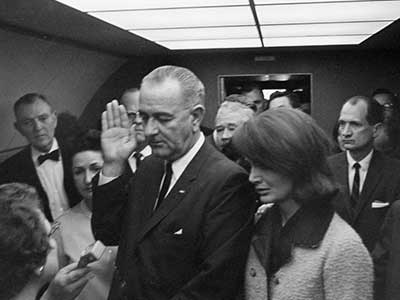 With a visibly shaken Jacqueline Kennedy at his side, Lyndon Baines Johnson assumed the oath of office onboard Air Force One at 1438 hours local, shortly before takeoff.