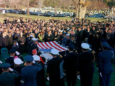 The graveside service takes place as the flag is held taut over JFK's casket.