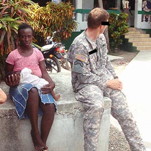 The mother and her baby wait with SSG Dave Ost while the HHF hospital staff at the Klinik Pep Bondye-a in Jérémie prepares the x-ray machine.