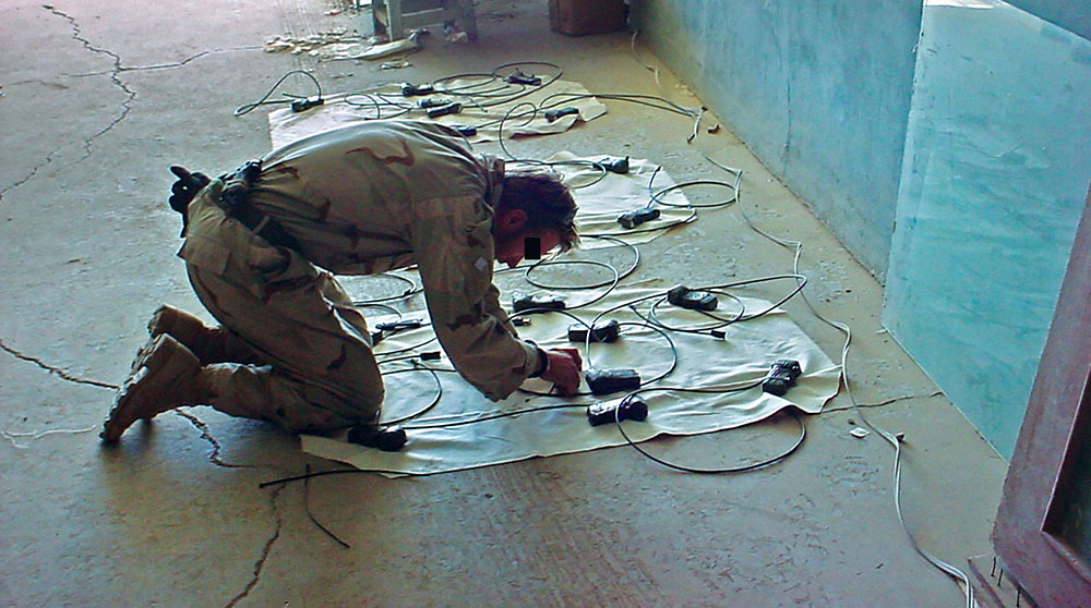 An SF Engineer Sergeant from ODA 512 constructs demolition charges for use in breaching mud and brick compound walls.