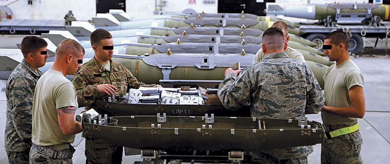 U.S. Army and Air Force personnel load a 750-pound M129 E2 bomb canister with MISTF-C leaflets
