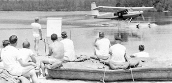 3/5th SFG personnel with RB-10 rubber boats beached watch the landing of the U-10A Super Courier float plane.