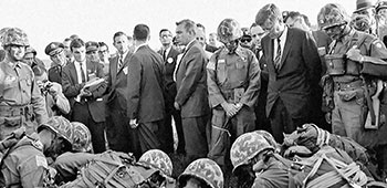 After the parachute jump President Kennedy was  briefed by paratroopers of the 82nd Airborne  Division near the Sicily Drop Zone viewing stand.