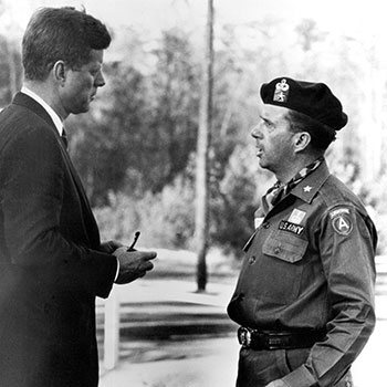 Brigadier General (BG) William P. Yarborough talked with President Kennedy following the 12 October 1961 special warfare demonstration at McKellar’s Pond. The visit had been arranged by the president’s aide-de-camp, Major General (MG) Chester V. ‘Ted’ Clifton, a West Point ’36 classmate.