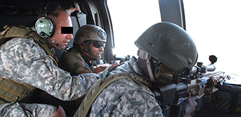 With a 160th Special Operations Aviation Regiment (SOAR) crewman (L) offering guidance, COL Alin Deb Saha (center) and a 1st SFG soldier practice aerial sniping techniques and provide over-watch for combined elements on the ground.