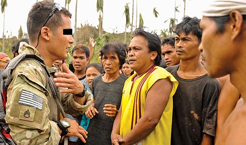 An NCO from Company A, 4-1st SFG talks with residents during a humanitarian relief mission in the Philippines after Typhoon Haiyan in November 2013.