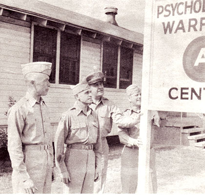 COLs Charles H. Karlstad (U.S. Army Psychological Warfare Center & School Commandant) and Aaron Bank (Center Executive Officer) with LTCs Lester L. Holmes (6th RB&L Group commander) and John O. Weaver (Psywar Division Chief of the Psychological Warfare School) pose by the Headquarters sign on Smoke Bomb Hill, Fort Bragg, NC.