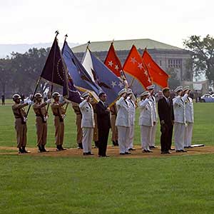 Surrounded by the USMA Color Guard (rear), the Secretary of the Army, Elvis J. Stahr, Jr. (left front), and various senior leaders, JFK (center front) receives honors from the USMA band and a 21-gun. Facing the President in the foreground of the photo is the honor guard.