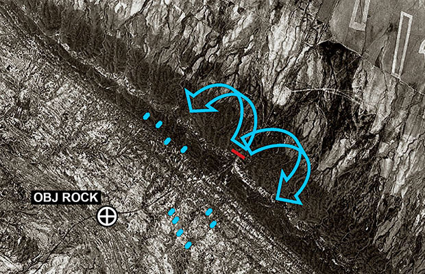 When the attack force encountered a large dirt roadblock just below the ridge that could not be breached quickly, the teams bypassed the obstacle by abandoning the road and crossing the ridge elsewhere.