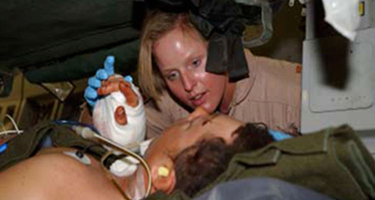 A critical care nurse with the 438th EAES, holds SFC Daniels’ (pseudonym) hand while she reassures him on his flight to Landstuhl Regional Medical Center in Germany.