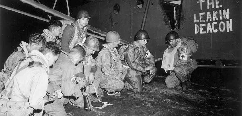 1st Airborne Task Force Headquarters personnel kneel in prayer before boarding their glider “The Leakin Deacon” for Southern France early the morning of 15 August 1944.