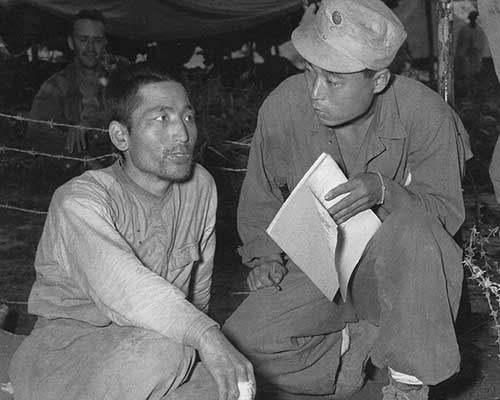 Each of the 5307th’s six combat teams had an assigned Nisei (second generation Japanese-American) interpreter for intelligence purposes. In this August 1944 photograph, Technical Sergeant Ed Mitsukado interrogates a Japanese prisoner being held at Myitkyina. The soldier had been found floating down the Irrawaddy River on a raft after the Americans prevailed at the Battle of Myitkyina. All of the Nisei assigned to the 5307th not only had native language proficiency, but many had trained at the Military Intelligence Service Language School in Minnesota. Even with experience and training in the Japanese language, many Nisei had difficulty communicating with captured soldiers having different dialects.