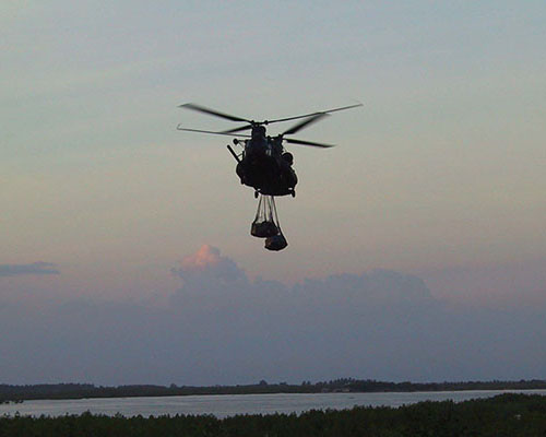 An MH-47E moves out at dusk with a sling-load of supplies.