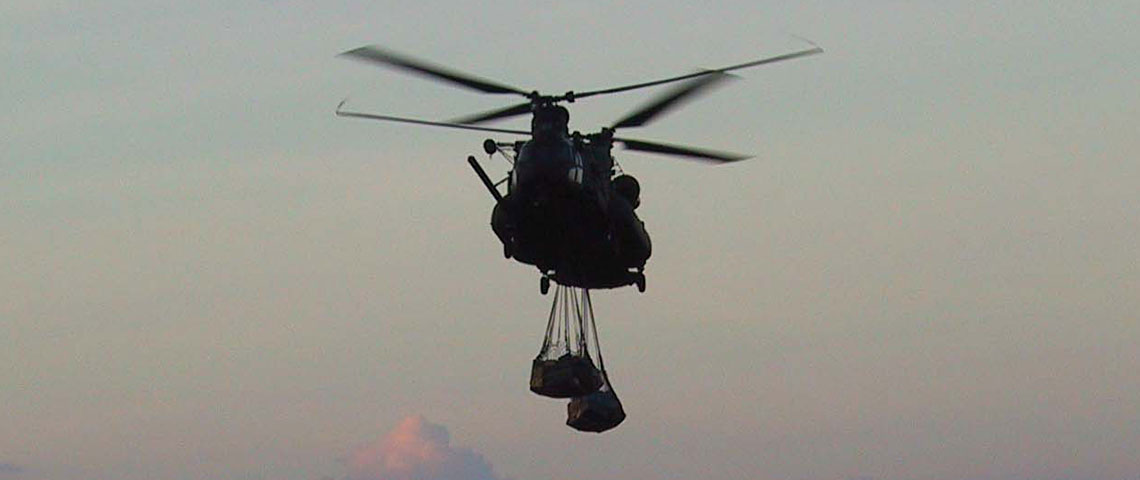 MH-47E moves out at dusk with a sling-load of supplies