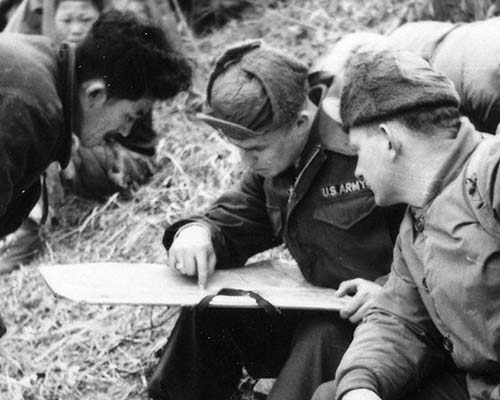 First Lieutenant Earl F. Thieme and an enlisted team member conduct a map reconnaissance for a suitable location for a cache. The plan to hide caches for stay-behind agents proved impractical.