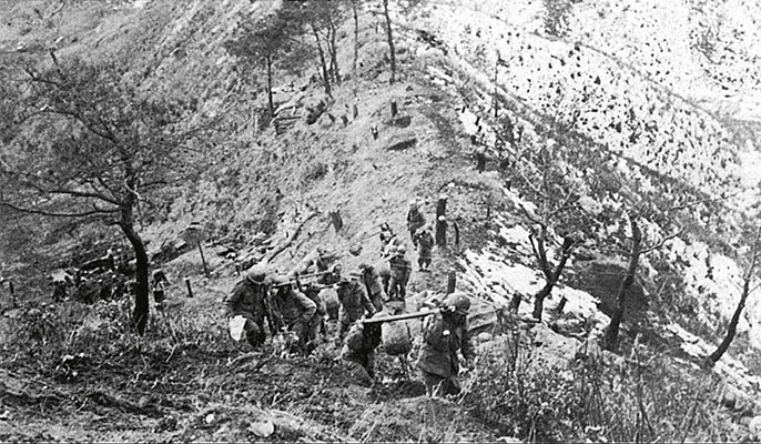 This photo of U.S. soldiers carrying barbed wire up to Old Baldy shows the exposed, narrow ridge available to resupply the beleaguered Colombians with ammunition.
