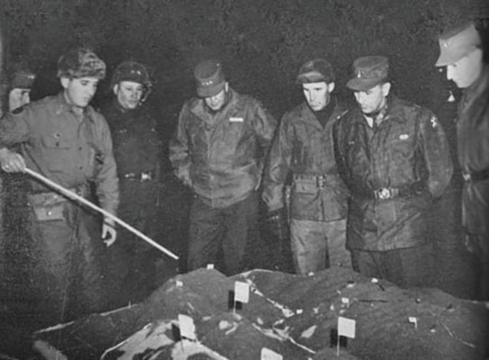 Captain Jorgé Robledo Pulido briefed Operation BARBULA (right to left) to General Mark W. Clark (UN Command), General Maxwell D. Taylor (Eighth U.S. Army), Colonel William B. Kern (31st Infantry), Lieutenant General Paul W. Kendall (I Corps), and Major General Wayne C. Smith (7th Infantry Division) with a sand table terrain model.