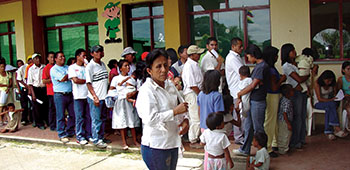 Locals wait for medical care outside the clinic. For many the free medical care offered during this MEDRETE may be the only medical care they can access. On the wall is the cartoon character used for CNP anti drug messages.