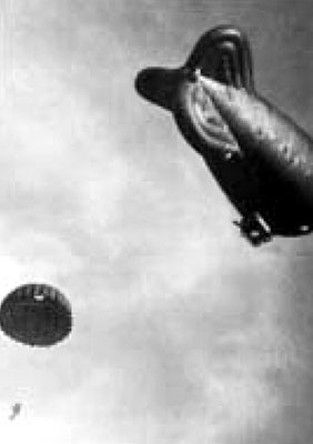 Parachutist descending after jumping from the moored barrage balloon.