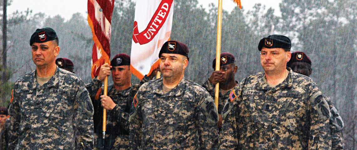 Colonel Hector Pagan, USASOC Deputy Commander, Colonel Ferdinand Irizarry, 95th Civil Affairs Brigade Commander, and Command Sergeant Major Timothy Strong, 95th Civil Affairs Brigade Command Sergeant Major, prepare to unveil the new 95th Civil Affairs Brigade Colors at Fort Bragg on 16 March 2007 during a rainstorm.
