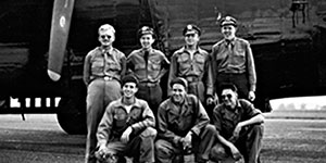 A Carpetbagger crew outside their B-24 Liberator that has been modified for night dropping operations. Notice the lack of a front turret, which was removed on Carpetbagger B-24s, and that the aircraft is painted all black.