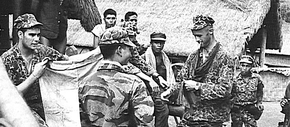 Captain Vernon Gillespie, the commander of A-312, on patrol with some of the Montagnard CIDG. Sergeant Lowell Stevens is on the left holding a captured Viet Cong flag.