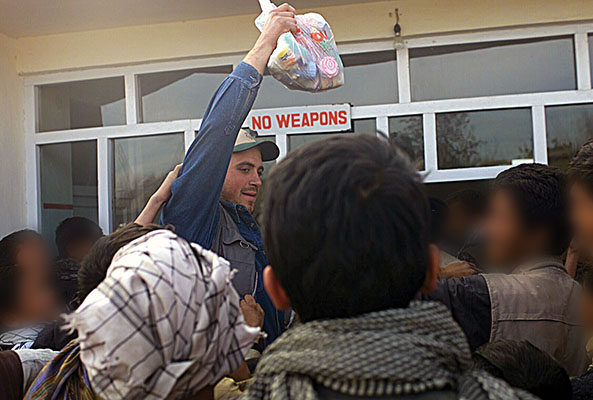 Specialist Jason A. Disney distributing Humanitarian Assistance items to the local population in Bagram.
