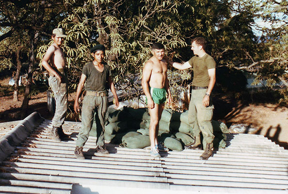 Two Salvadoran soldiers help Sergeant First Class Jorge Reyes and Sergeant Kenneth Beko carry sandbags up to the rooftop defensive position.