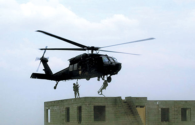 Rangers fast rope on to a rooftop from a UH-60A Black Hawk.