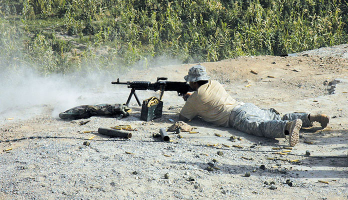 >A Special Forces soldier fires his M-240B machine gun at Taliban fighters moving toward Sperwan Ghar.