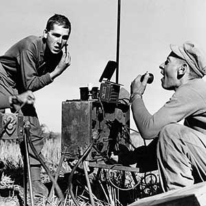 Members of MARS Task Force in Burma used radios to arrange for aerial resupply when operating behind Japanese lines. The hand-cranked generator supplied power for the radio, here doubling as  a mirror stand.