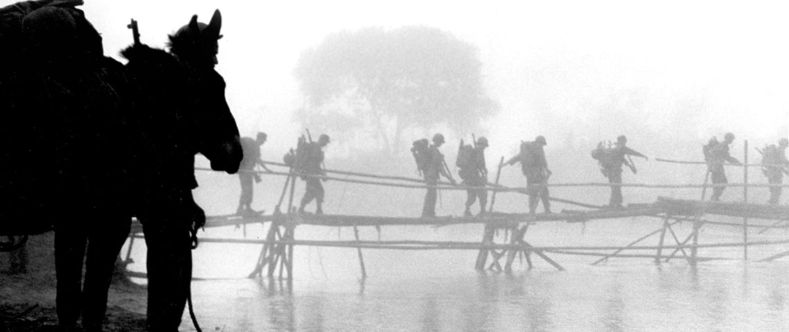 MARSmen use a bamboo bridge to cross a river in Burma.