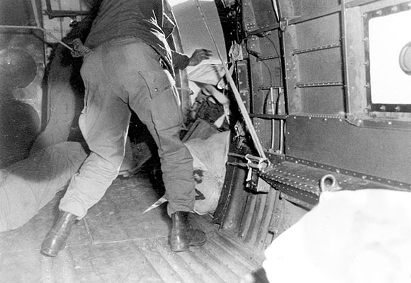A kicker pushes supplies out the aircraft cargo door to a Detachment 101 group in Burma, 1944-45.
