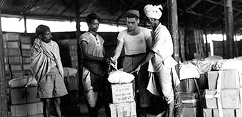 3. Detachment 101 supply personnel in India tie together cases of corn, peas, and spinach for air drop. Locally-hired laborers helped package the loads.