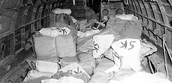 7. The interior of a C-47 cargo aircraft loaded with supplies for air drop. Most are burlap (jute) wrapped packages.