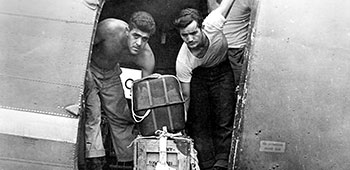 9. OSS personel demonstrate how they pushed supplies out of the aircraft. Notice there are no safety straps and the parachute is simply boxed.